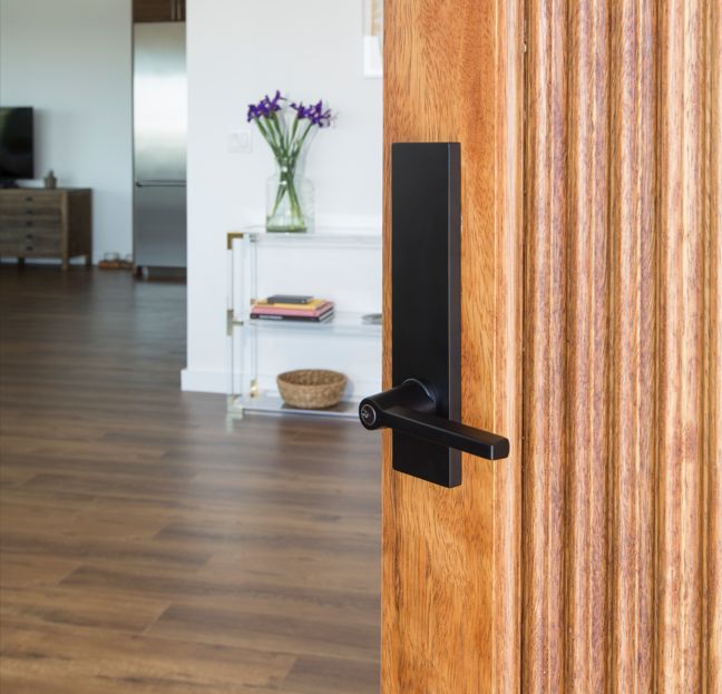 Modern zwart deurbeslag op een houten binnendeur.