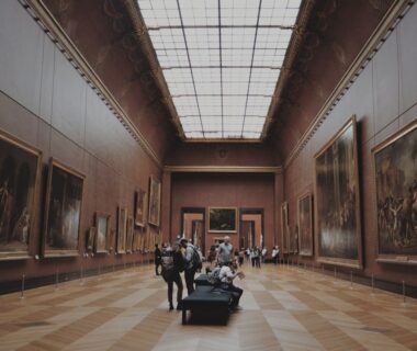 Historische museumzaal met schilderijen, bezoekers en een groot glazen dak