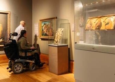 Bezoeker in rolstoel bekijkt kunstwerken in een museumzaal