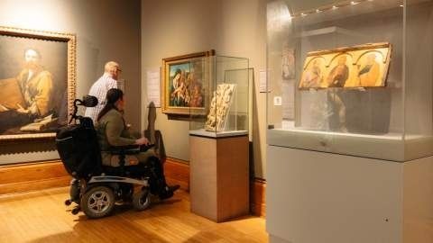 Bezoeker in rolstoel bekijkt kunstwerken in een museumzaal